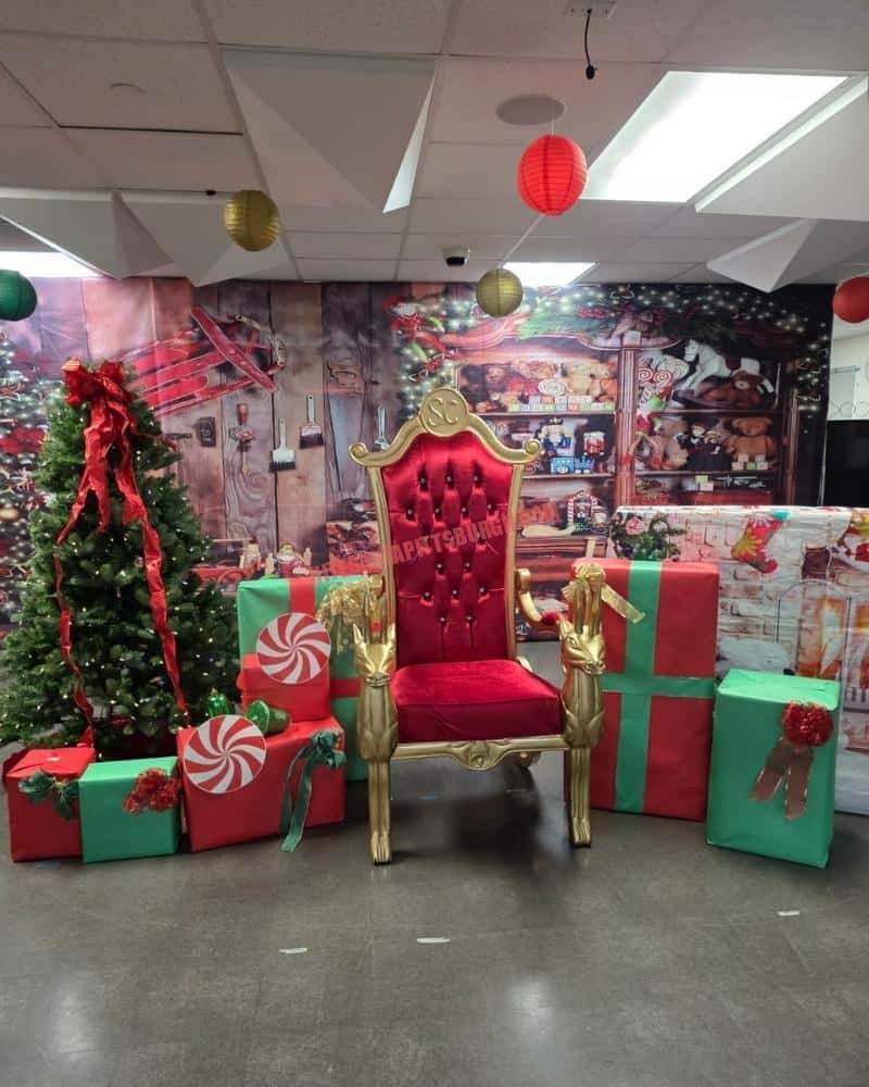 Red and gold Santa throne with reindeer armrests set up for an office party photo area