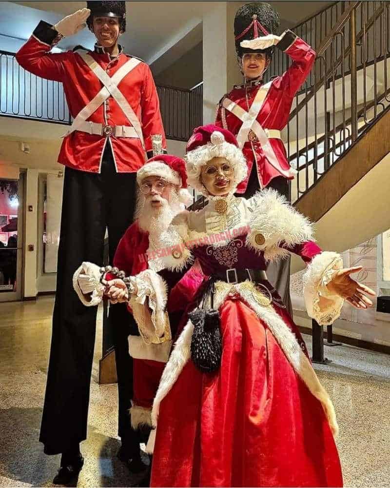 Corporate Santa and Mrs. Claus with two nutcracker soldiers on stilts at a company Christmas party