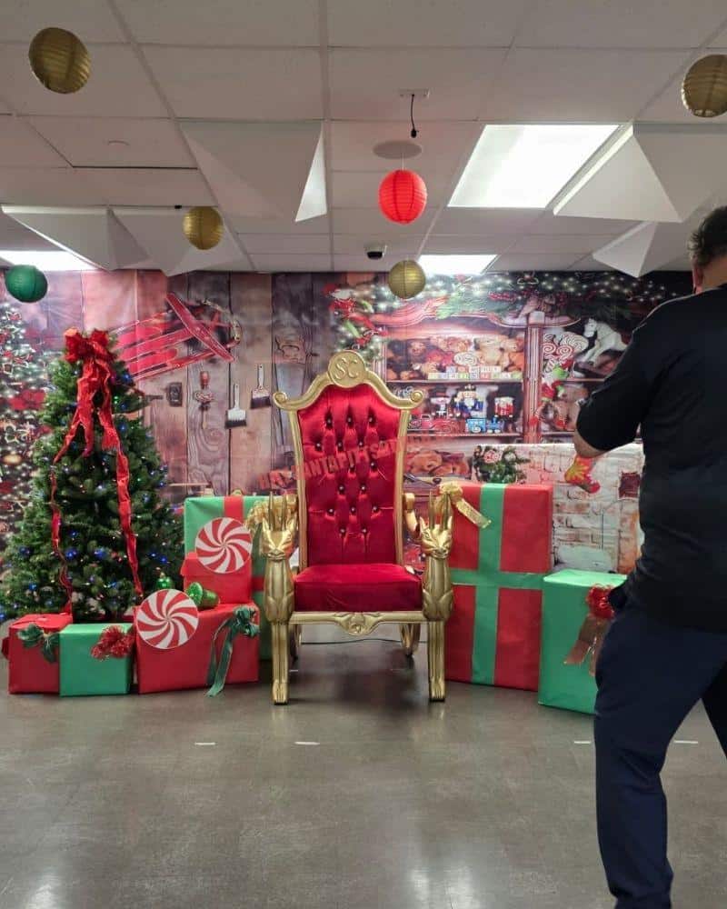 Santa photos set with a red and gold throne, Christmas tree and gift boxes as a photographer prepares